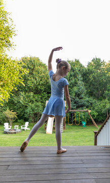 Vertical image Young girl doing ballet on porch of home 