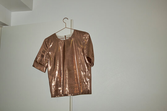 Golden shiny metallic t-shirt hanging on door with hard direct flash