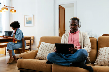 Cheerful black couple working at home in a bright livingroom