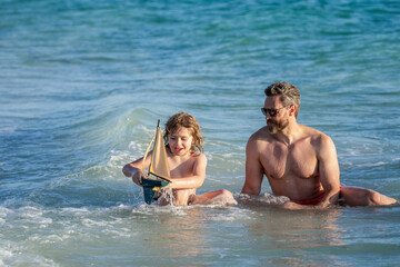 Father son beach adventure playing with toy ship together