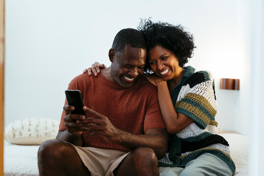 Cheerful couple using smartphone in a bright home - Powered by Adobe