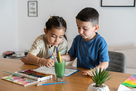 Budding Artists.Siblings Expressive and Engaged in Watercolor Fun.