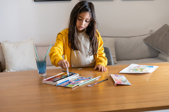Creative Inspiration. Girl in Yellow Hoodie Painting with Watercolors.