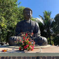 View of the giant Buddha statue with flowers at the Jodo Mission and Temple in historic Lahaina Maui Hawaii