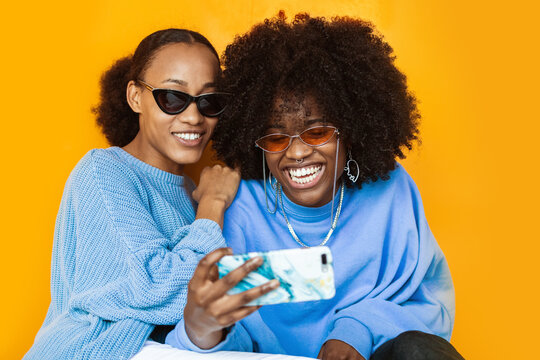 Stylish girlfriends taking selfie on smartphone
