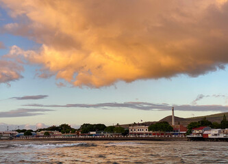 Bright orange sunset and clouds over the Pioneer Mill and Front Street downtown Lahaina on Maui Hawaii as seen from the waterfront