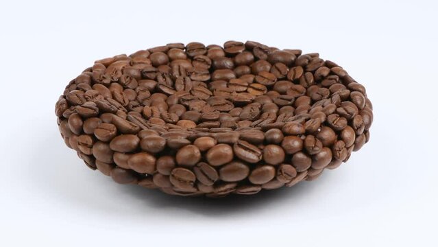 A plate made of coffee beans on white. Side view. Loop motion. Rotation 360. 4K UHD video footage 3840X2160.