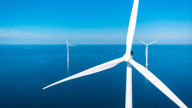 offshore windmill park with clouds and a blue sky, windmill park in the ocean aerial view with wind turbine Flevoland Netherlands Ijsselmeer. Green Energy in the Netherlands on a sunny day