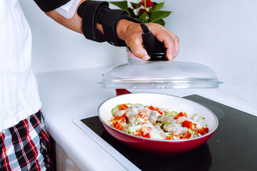 Man with adjustable elbow brace preparing food