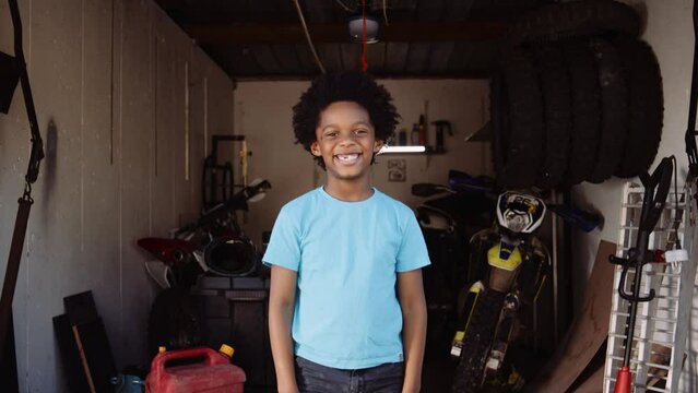 Wide portrait young boy smiling at camera in home bike workshop in garage
