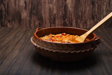 Authentic mexican chicken tinga, typical mexican food prepared in a clay pot on a wooden table.