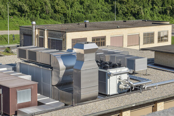 hvac ventilation system on a roof in front of a industrial building, chiller and cooler next to a monobloc