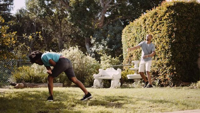 Mixed race father playing catch with football in the garden