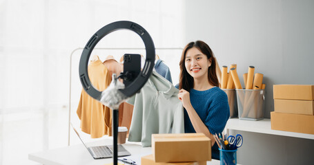 Young woman running online store Startup small business SME, using smartphone or tablet taking receive and checking online purchase shopping