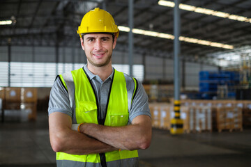 Portrait of caucasian male factory worker looking at camera with his arms crossed confidently in the process of working in warehouse.