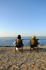 a couple of man and woman are sitting on the beach and relaxing