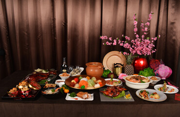 chinese new year festival asian food cuisine with meat, vegetable, noodle, cookies and yusheng lo hei with sakura flower lantern decoration on bronze background restaurant banquet halal dining menu