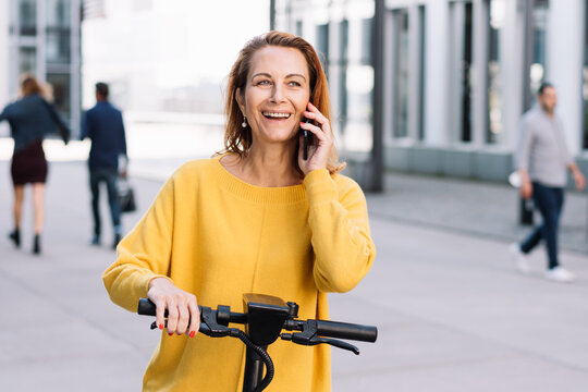 Active Senior Woman in the City: Phone Call and E-Scooter Ride