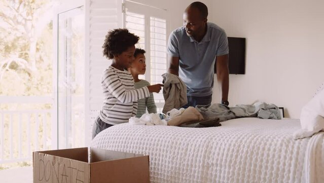 Young Black family sorting and purging donation clothing together in newly renovated home