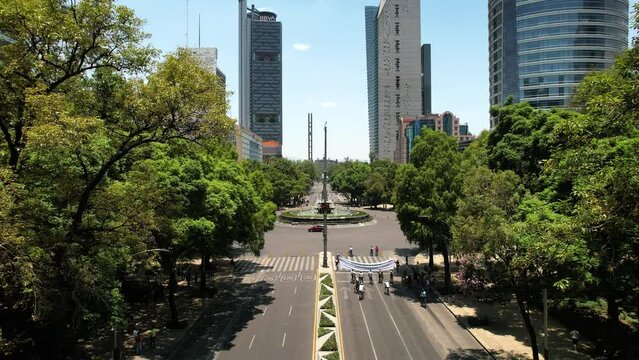 backwards drone shot of cyclists exercising on reforma avenue in mexico city during sunny day