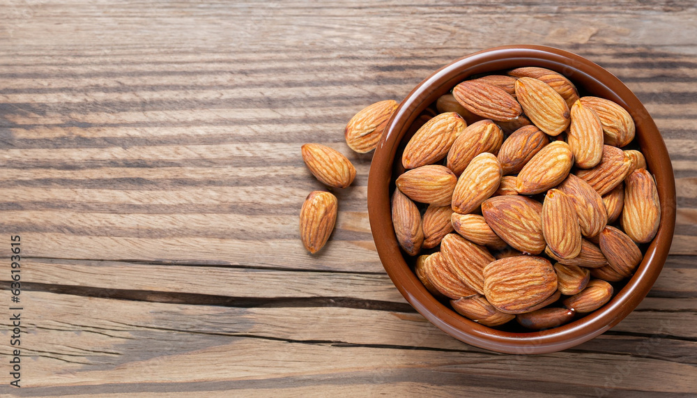 Wall mural almonds in brown bowl on textured wooden background, top view. copy space on left side - Wall murals