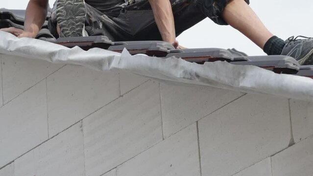contractor builder laying fired ceramic tiles on the roof