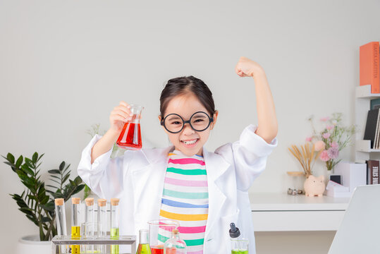 Asian little girl working with test tube science experiment in white classroom
