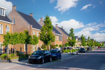 Dutch Suburban area with modern family houses, newly built modern family homes in the Netherlands, nice and comfortable neighborhood. Some homes on the empty street in the suburbs of Urk Flevoland - obrazy, fototapety, plakaty