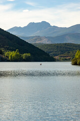 Imagen vertical con personas practicando deportes acuáticos en el lago de montaña al atardecer.