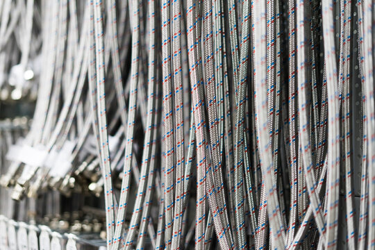 Closed up braided stainless steel texture of flexible hose arranged in a row against white wall.