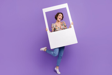 Full size photo of attractive young woman hold instant photo frame dressed stylish flower print clothes isolated on purple color background