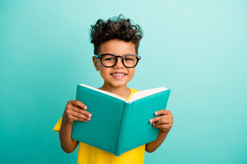 Photo of diligent nice schoolboy with brown hair dressed yellow t-shirt holding book read story...