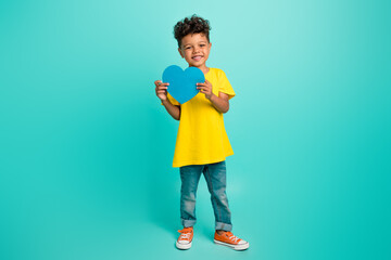 Full length photo of charming schoolboy heart postcard valentine day wear trendy yellow garment isolated on aquamarine color background