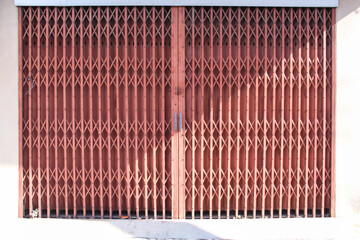 Old rusty red steel shutter door with seamless patterns house front wall background with sunshine
