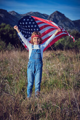 Happy preteen boy with waving USA flag over head