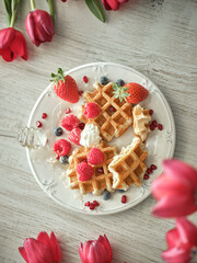 Sweet waffles on table with tulips