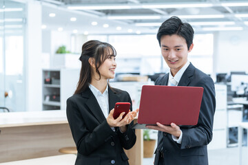 パソコンで仕事する新人ビジネスマン男女