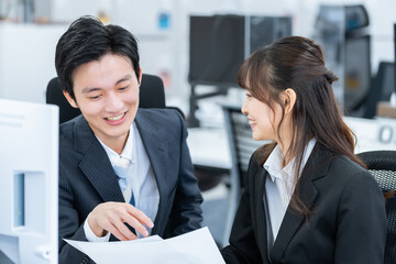 オフィスで話す新人ビジネスマン男女
