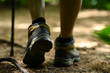Male legs with hiker boots walking along the forest path. Traveling and adventure concept.