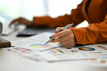 Closeup, select focus on woman hand choosing colors from color swatch samples chart on wooden desk.