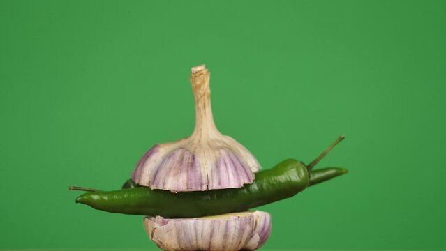 rotating young garlic with hot pepper inside on a green background