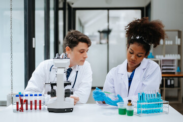 Focused mature male doctor and African female nurse look at tablet and laptop screen discuss anamnesis together. Concentrated diverse medical professionals
