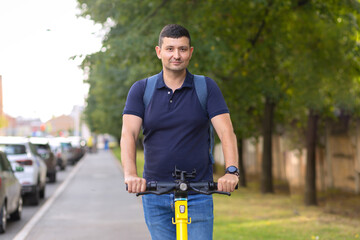 Adult man on electric scooter with backpack goes to work on street in city. Active man resting, traveling, working on e-scooter. People on eco-friendly urban transport
