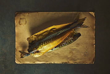 Smoked mackerel fish on an old paper. Top view
