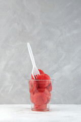 Watermelon pieces in disposable plastic cup with fork.