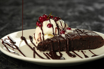Chocolate brownie with ice cream and berries on a black background