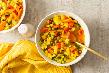 Minestrone soup from zucchini and tomato, onion and carrot, corn and peas with parsley, top view of...