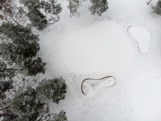 Aerial view of a golf cart with fairway, bunkers and putting green covered with snow. Photography taken from above with a drone in Sweden in winter. 
