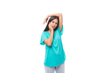 Fototapeta premium young caucasian female model with black straight hair is wearing a blue t-shirt on a studio white background with copy space