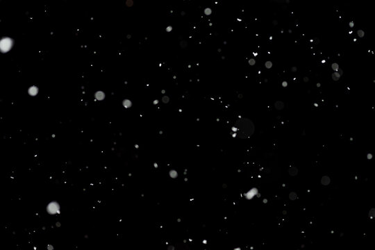 Bokeh effect of snowfall and lights. Abstract blurred background with snowflake in the night sky, White spots and dots in the dark. Snowy stormy weather, falling snow